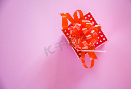 活动礼盒摄影照片_红色情人节概念礼盒/粉色背景带蝴蝶结的红色礼盒