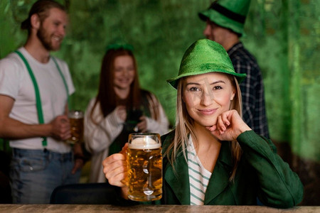 圣帕特里克框摄影照片_正面视图微笑的妇女与帽子庆祝圣帕特里克节与饮料朋友