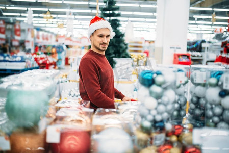 年轻人在超市挑选圣诞装饰品，节日购物是一种传统。