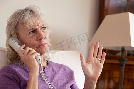 老年妇女在家中接到不想要的电话