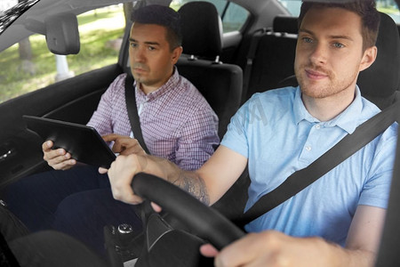 司机课程和人的概念-人和驾校教师，车里有平板电脑。汽车驾驶学校教员兼青年司机