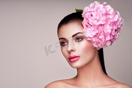 波特雷特模型，头上装饰着大朵粉色的花。浓妆艳抹的黑发女子。完美的皮肤。睫毛。化妆品眼影