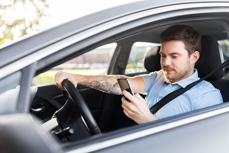 运输、车辆和技术概念—微笑的男子或司机驾驶汽车和使用智能手机。男子驾驶汽车和使用智能手机
