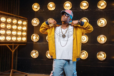 戴帽子的黑人说唱歌手,在舞台上表演,背景是聚光灯.