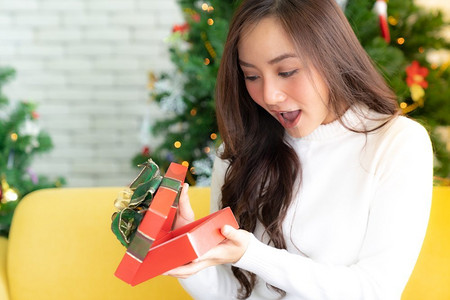 礼物盒子打开摄影照片_美丽的快乐的亚洲女孩打开圣诞节礼物盒子圣诞节假日季节问候。