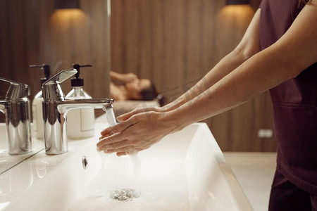 女按摩师摄影照片_女按摩师洗手前按摩程序在水疗沙龙。按摩和放松，身体和皮肤护理