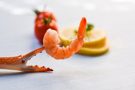 贝类海鲜虾在煮蟹爪/虾虾海洋美食晚餐和番茄柠檬在白色桌子背景 
