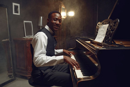大黑人摄影照片_乌木大钢琴演奏家，俱乐部爵士乐表演。黑人表演者在演奏旋律前摆姿势