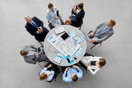 人，工作和企业概念—业务团队与gdgets和文件在圆桌办公桌。业务团队与gdgets和文件在办公室