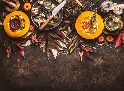 秋天季节食物背景与一半南瓜，刀，草药和香料在黑暗的乡村背景与秋天叶子。俯视图。边境