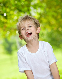 肖像的笑大声男孩反对夏季花园