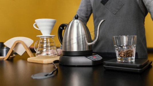水果茶壶摄影照片_前视男咖啡师用茶壶滤嘴煮咖啡