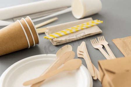 餐具刀和叉摄影照片_回收，餐具和环保概念—一次性餐具的纸和木材在灰色背景。纸和木制的一次性餐具
