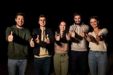 休闲和人的概念-一群快乐微笑的朋友晚上在户外竖起大拇指.合照合影