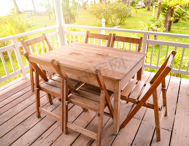 套木桌用餐和椅子在阳台露台有前院绿草和夏季花园背景 