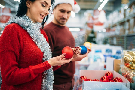 幸福夫妻在超市挑选圣诞树球，这是家庭传统。12月份假日购物