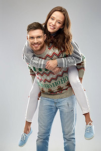 圣诞节，人和假日概念—快乐夫妇的肖像有乐趣在丑陋的毛衣党。快乐的夫妇在圣诞节丑陋的毛衣党