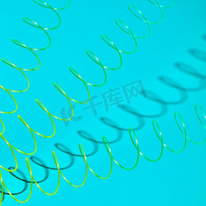 三个彩色玩具螺旋与柔和的阴影在柔和的绿松石背景上，文字的位置。伸展着带阴影的塑料弹簧。