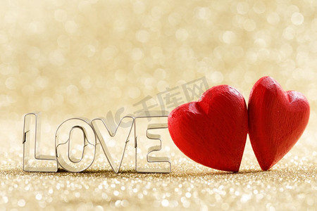 两颗红色手工制作的木心和文字爱情在金色明亮的闪光灯下闪耀着波克背景。木质的心和文字的爱