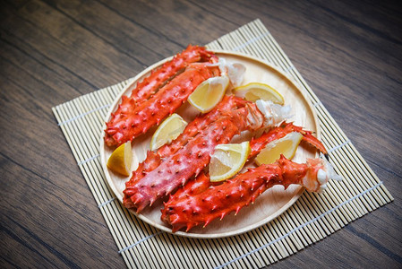 桌子上的木盘里有阿拉斯加帝王蟹腿煮的柠檬香料海鲜/北海道红蟹