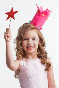 美丽的小糖果公主女孩在皇冠持有星形的魔杖。戴着魔杖的女孩