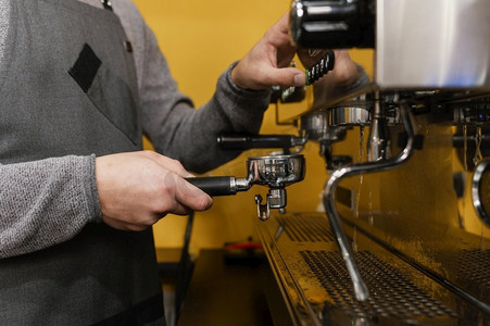 使用图示摄影照片_带围裙的男性咖啡师使用专业咖啡机