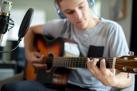 十几岁的男孩在家里玩吉他和录制音乐