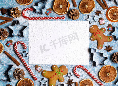 圣诞白色背景摄影照片_圣诞食品架。姜饼饼干，香料和装饰在蓝色背景与复制空间在空白卡片.圣诞食品架
