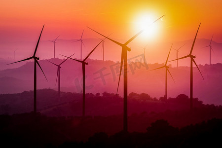 全球发展摄影照片_日落时分，风力涡轮机在山上的剪影。可再生清洁能源概念及风能可持续发展业务。