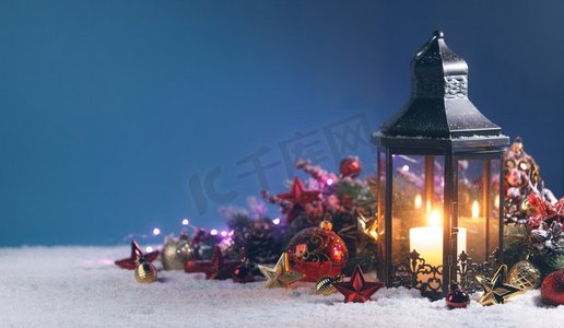 蓝色元宵灯笼摄影照片_灯笼和红色和金色圣诞节装饰在雪在蓝色背景。灯笼和圣诞装饰