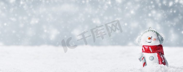 圣诞雪人玩具，背景是冬天的雪地。冬日背景下的雪人玩具