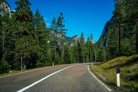 驱动传送带摄影照片_美丽的山路与树木，森林和山脉的背景。拍摄于意大利多洛米蒂山的国道公路。