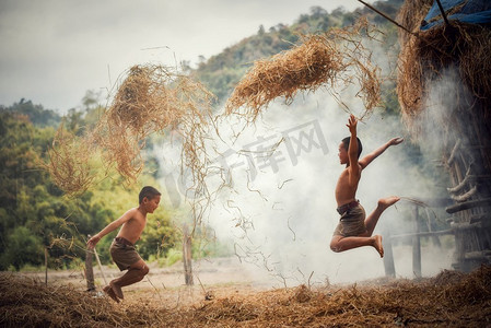 可爱跳跃摄影照片_亚裔男友小朋友快乐有趣的跳跃和玩稻草在农村农庄生活的小朋友乡下人