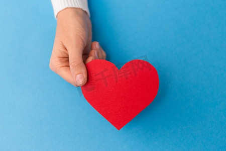 爱情、健康和情人节S日概念-手持红色心形，蓝色底色。蓝色背景上手持红心形