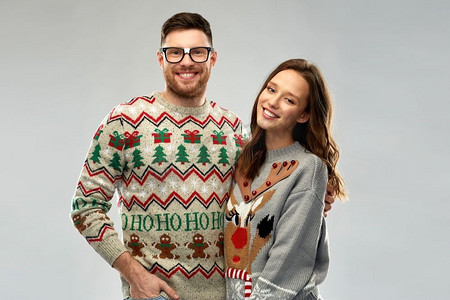 圣诞节标题框摄影照片_圣诞节，人和假日概念—在丑陋的毛衣党的幸福夫妇肖像。快乐的夫妇在圣诞节丑陋的毛衣党