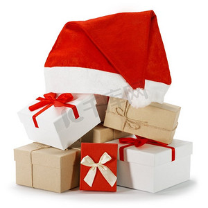 红白相间的圣诞礼品盒上盖着圣诞老人帽，白色背景隔开。圣诞礼物和圣诞帽