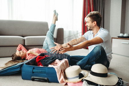 年轻夫妇收拾他们的行李箱度假。旅行概念费。行李准备。年轻夫妇打包他们的行李箱度假