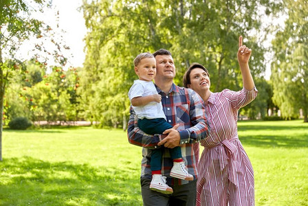 家庭，休闲和人的概念—快乐的母亲，父亲和小儿子仰望夏季公园。夏日公园快乐家庭