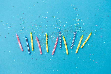 节日、庆典和派对概念-蓝色背景上洒有洒水的生日蜡烛。蓝色背景上有洒水的生日蜡烛