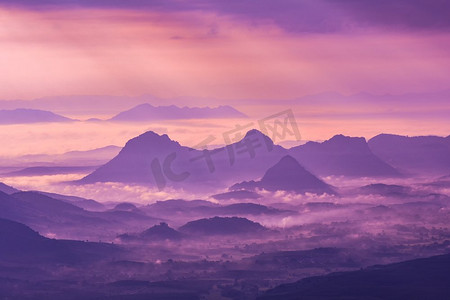 风景山有雾雾紫色天空和升起的太阳在上午在小山—剪影山脉背景