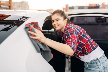 妇女在自助洗车机上清洗后擦拭汽车。清洁车辆的女士。妇女擦拭汽车、自助洗车
