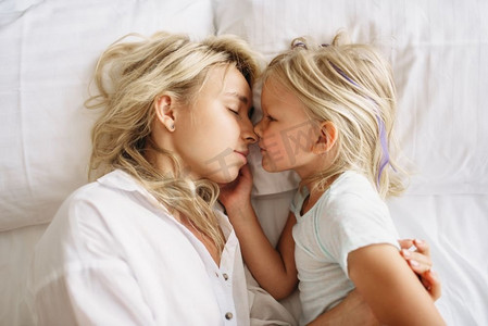 快乐时光摄影照片_母亲和孩子睡在床上在家里，顶视图。父母的感情，团聚，快乐时光