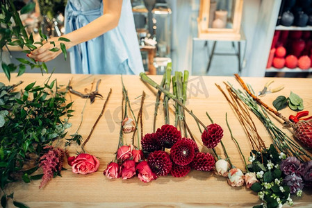 有不同品种的鲜花的表在花店，背景的女性花店。插花制作
