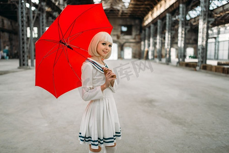 漂亮的动漫风格的金发女孩与红色的伞。Cosplay时尚，亚洲文化，娃娃在衣服，可爱的女人化妆在工厂店