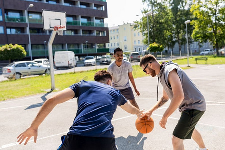 街头篮球摄影照片_体育、休闲游戏和男性友谊概念—一群男人或朋友打街头篮球。一群男性朋友打街头篮球