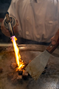 烹饪牛肉铁板烧食谱日本烤牛肉在烹饪锅与刮刀和燃气燃烧器火焰