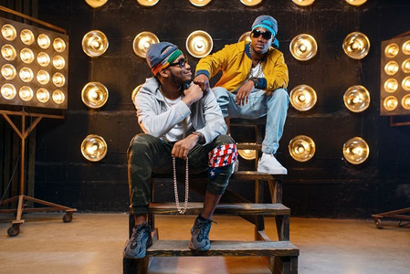 两个戴着墨镜的黑人说唱歌手,在舞台上表演,背景是聚光灯.