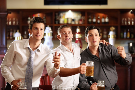 男性观众摄影照片_年轻男子与啤酒观看比赛在酒吧
