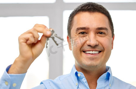 房地产企业摄影照片_房地产企业、房地产和人的概念——快乐的微笑男人拿着钥匙。快乐的微笑男人拿着钥匙