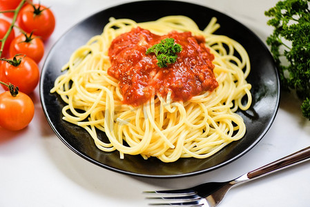 意大利面供应在黑色盘子与番茄和欧芹在餐厅意大利食品和菜单概念/意大利面顶视图